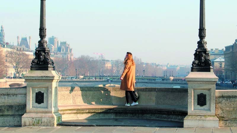 Mujer en un puente mirando el paisaje durante sus vacaciones